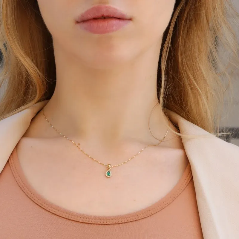 A drop-shaped halo pendant with a green zircon stone on a 14K gold Venetian chain.